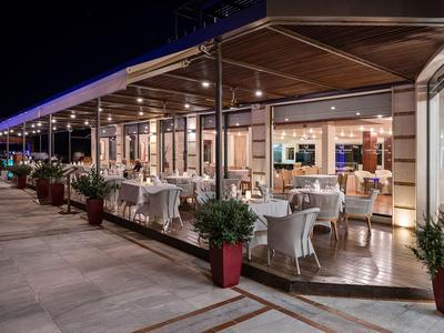 Terrasse de restaurant extérieure en soirée avec tables dressées et places assises dans un hôtel.