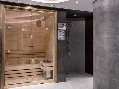 Sauna moderne avec bancs en bois, façade en verre et douche intégrée dans un cadre élégant.