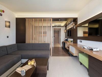 Chambre d'hôtel moderne avec canapé, bureau et design minimaliste aux tons neutres.