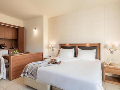 Chambre d'hôtel lumineuse avec grand lit, mobilier en bois et éclairage chaleureux.