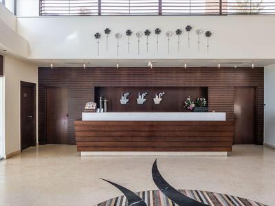 Réception d'hôtel moderne avec panneaux en bois, sol carrelé clair et éléments décoratifs.