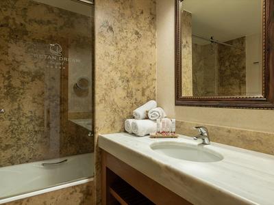 Salle de bain moderne avec lavabo en marbre et baignoire intégrée dans des tons chauds.