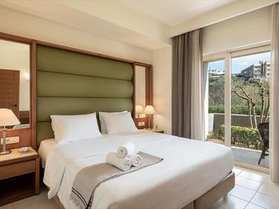 Chambre d'hôtel lumineuse avec lit double, lampes de chevet et vue sur un balcon avec nature.
