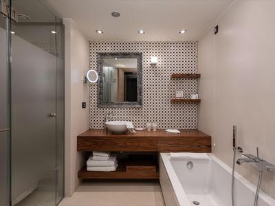 Salle de bain moderne avec meuble-lavabo en bois, baignoire et mur d'accent en carreaux décorés.