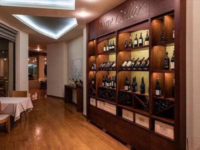 Espace hôtelier élégant avec cave à vin éclairée et tables dressées sur parquet.