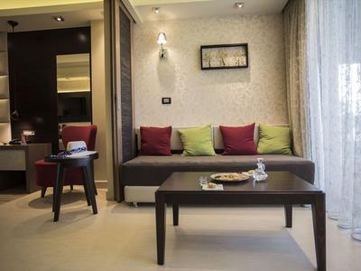 Chambre d'hôtel moderne avec canapé, coussins colorés et rideaux.
