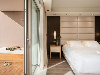 Chambre d'hôtel moderne avec lit double, tables de nuit et porte de balcon en verre.