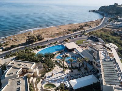 Vue aérienne d'un hôtel avec piscine et côte, adjacent à une route et à la mer.