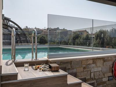 Piscine avec garde-corps en verre et escaliers, entourée par la nature et une maçonnerie élégante.
