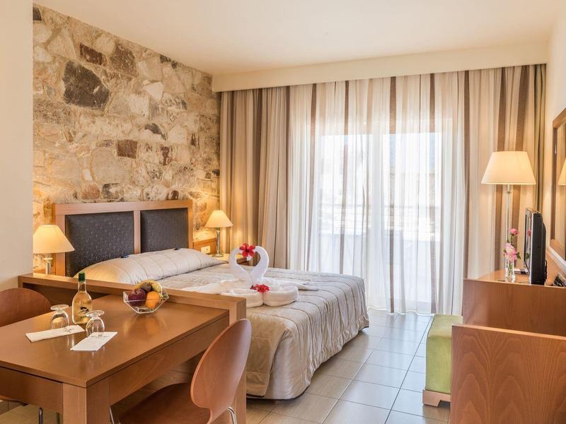 Bright hotel room with two single beds, desk, and stone accent wall.