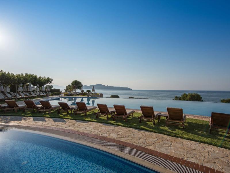 Infinity pool with lounge chairs overlooking the sea under clear sky