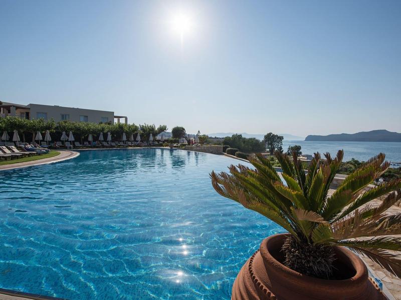 Large pool with sun loungers and sea view under a sunny sky