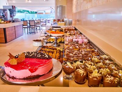 Buffet mit einer Vielzahl von Desserts und Kuchen in einem modernen Speisesaal.
