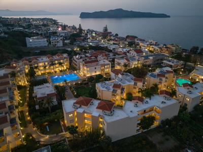 Aerial view of coastal town with lit buildings and pools at dusk