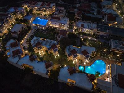 Night view of a lit hotel complex with multiple pools in a city.