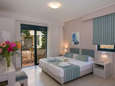 Brightly decorated hotel room with double bed and access to a terrace.