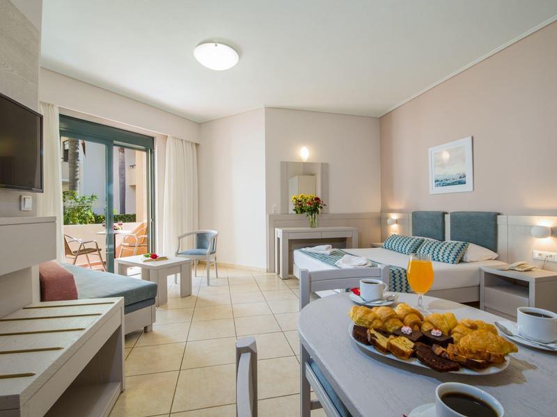 Modern hotel room with balcony, table, chairs, and breakfast setup.
