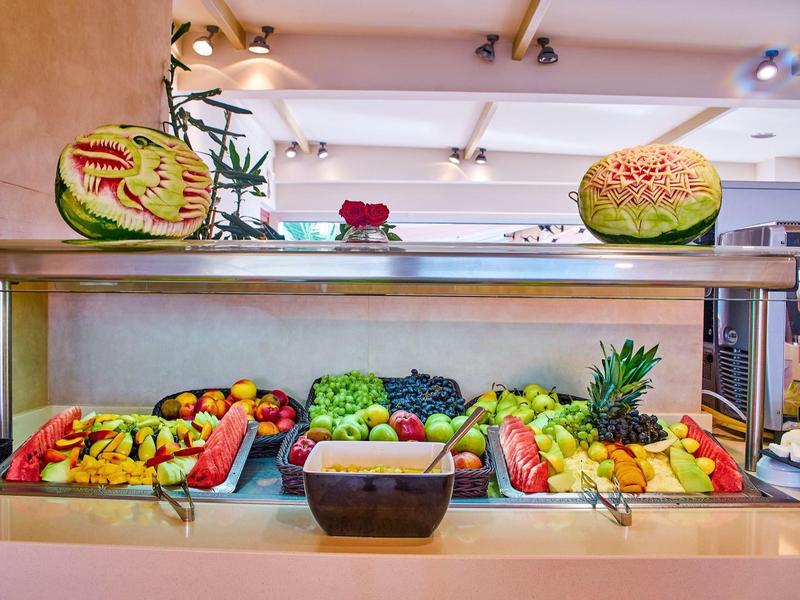 Colorful fruit platters with artistically carved melons in a buffet area.