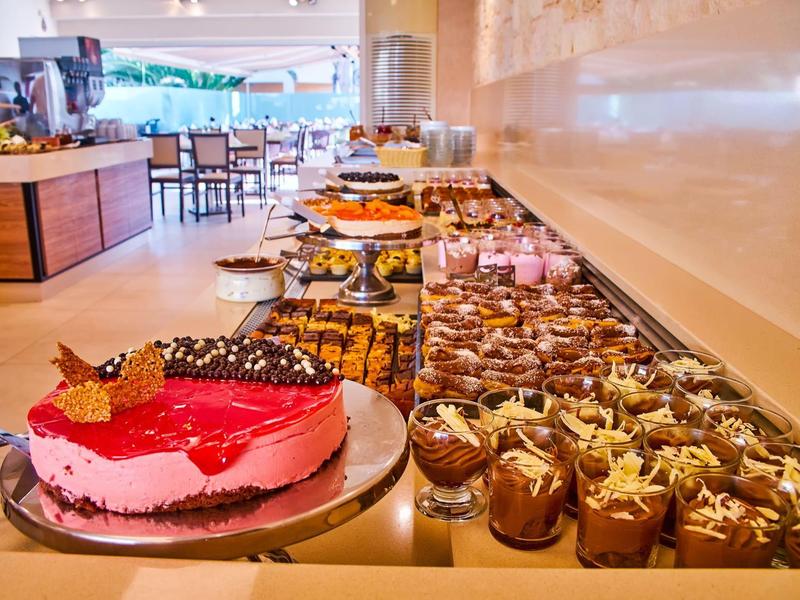 Buffet with various desserts and cakes in a bright restaurant.