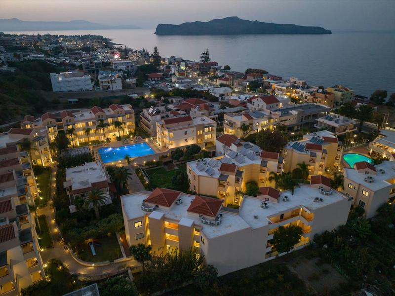 Aerial view of coastal town with lit buildings and pools at dusk
