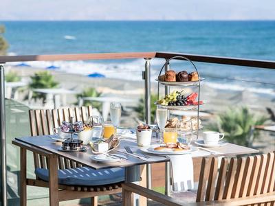 Terrassenfrühstück mit Meerblick, gedeckter Tisch und Stufenplatte mit Speisen.