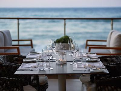 Eleganter gedeckter Tisch mit Blick auf das Meer und gemütliche Stühle.