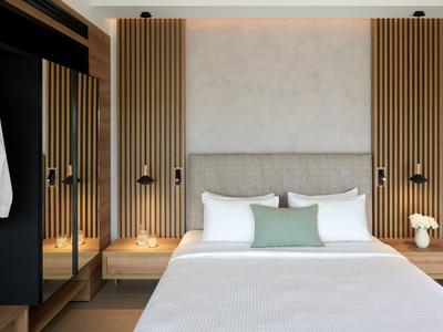 Chambre d'hôtel moderne avec lit double, éléments en bois et dressing.