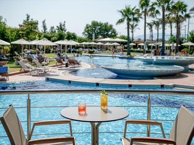 Zone de piscine d'hôtel avec chaises longues, parasols et tables au premier plan.