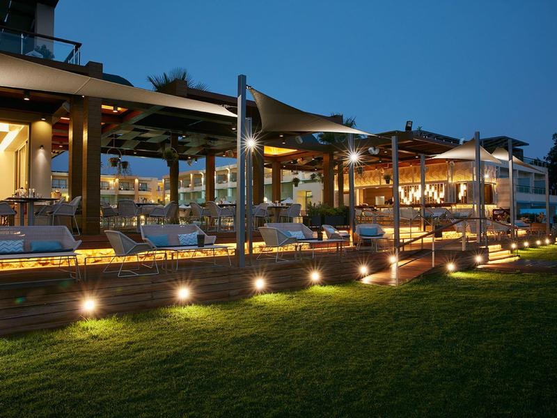 Osvětlená venkovní posezení v hotelu večer s trávníkem v popředí
