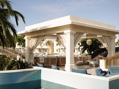 Padiglione bianco moderno con aree salotto accanto a una piscina e palme sullo sfondo