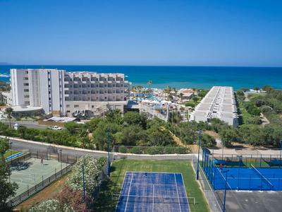 Complesso alberghiero con campi da tennis in primo piano, paesaggio verde e mare sullo sfondo