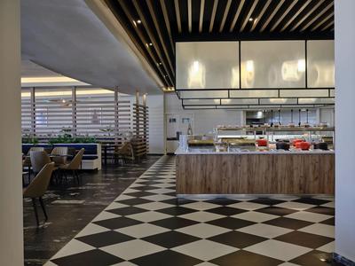 Ristorante moderno con pavimento a scacchi bianco e nero e cucina a vista.