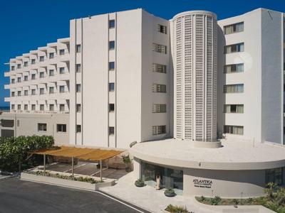 Edificio alberghiero bianco moderno con più piani e area d'ingresso rotonda sotto un cielo limpido.