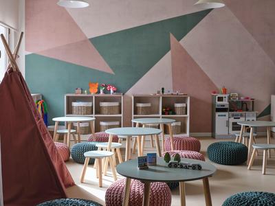 Accogliente area lounge dell'hotel con sgabelli colorati, tavoli e design geometrico delle pareti.