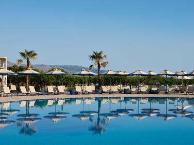 Großer Hotelpool mit Liegestühlen und Sonnenschirmen unter blauem Himmel