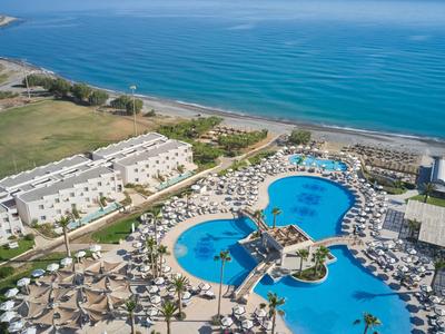 Blick auf ein Hotelresort mit großen Pools neben dem Meer und Sonnenschirmen auf der Terrasse.