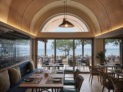 Elegantes Restaurant mit runden Decken, Blick auf Terrasse und Meer bei Tageslicht.