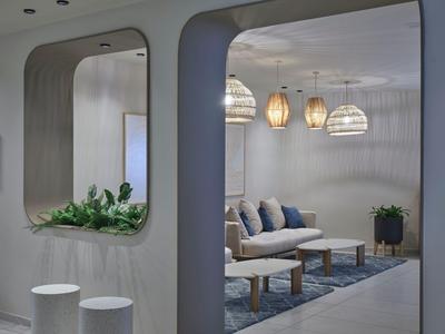 Modern eingerichtetes Wohnzimmer mit bequemen Sitzmöbeln, Teppich und hängenden Lampen.