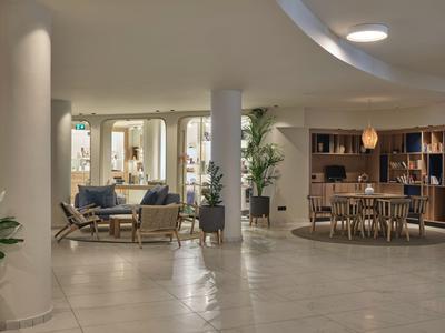 Moderner Hotel-Loungebereich mit Sitzgruppen, Pflanzen und warmem Licht.