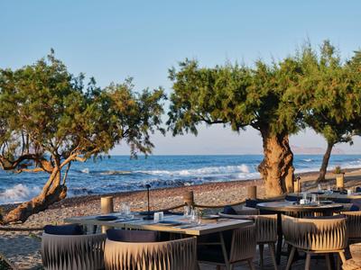 Außerhalb gelegener Essbereich mit Blick auf den Strand und das Meer bei klarem Himmel.