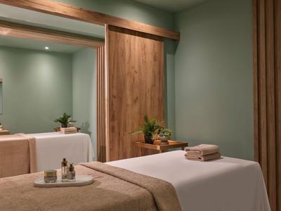 Salle de soins avec table de massage, éclairage doux et décoration apaisante.