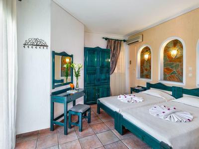 Hotelkamer met twee eenpersoonsbedden, groen meubilair en warme muren met wanddecoratie.