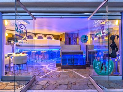 Moderne hotel zwembad met blauw verlichte ligstoelen en glazen wanden.