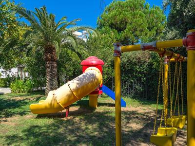 Speeltuin met glijbaan en schommels in een groen park onder een blauwe lucht