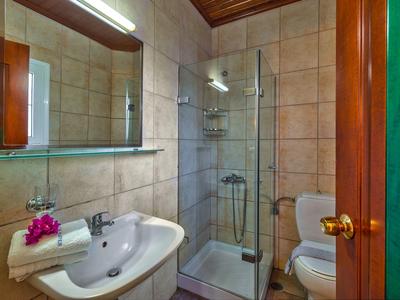 Compacte badkamer met wastafel, toilet en douchecabine in warm licht.