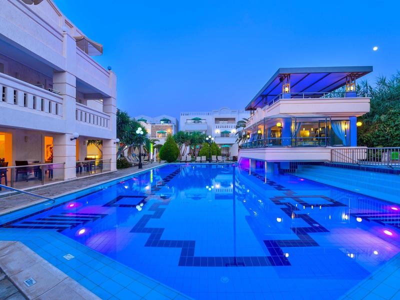 Modern hotelzwembad met blauw licht en verlichte zitgedeeltes bij schemering.
