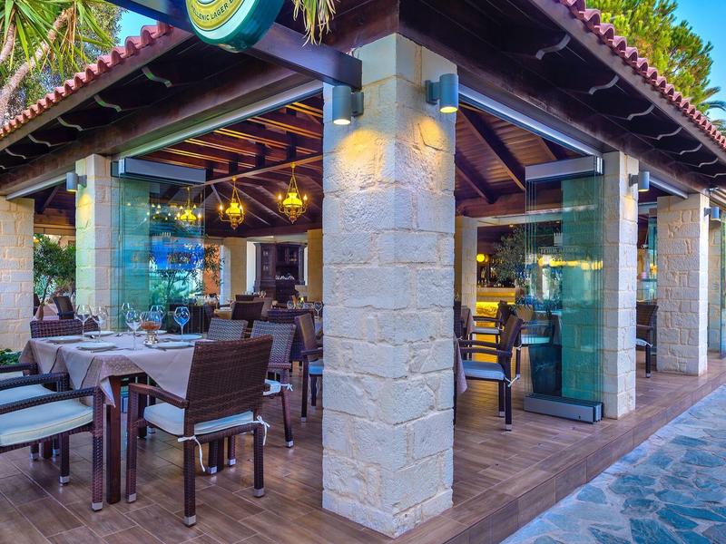 Open terras met tafels en stoelen bij een hotel met warme verlichting en houten plafond.