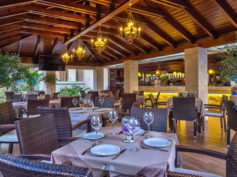 Elegante restaurantinterieur met houten balkenplafond, gedekte tafels en bar op de achtergrond.