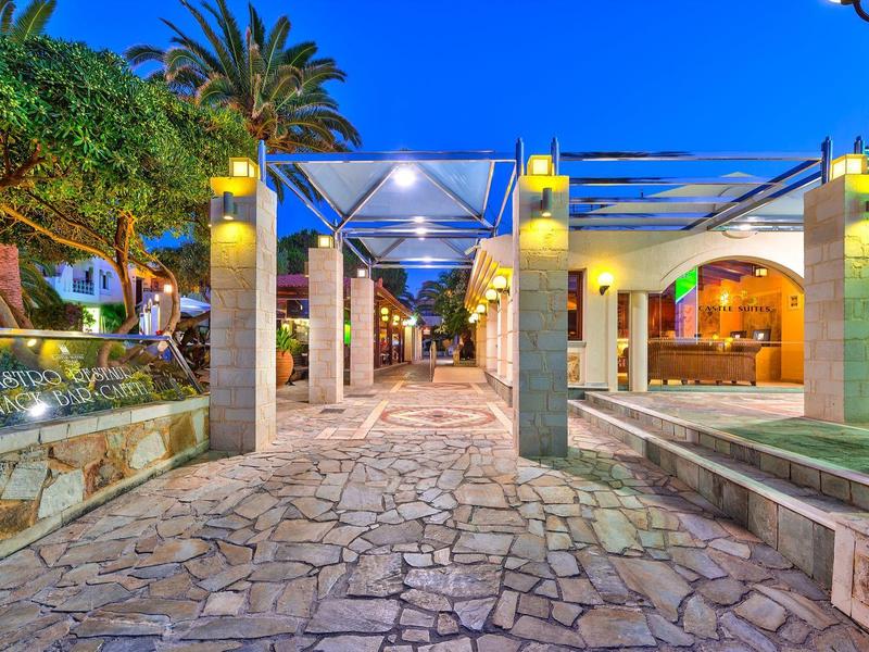 Verlichte wandelweg met zuilen en planten in een tropisch resort 's nachts