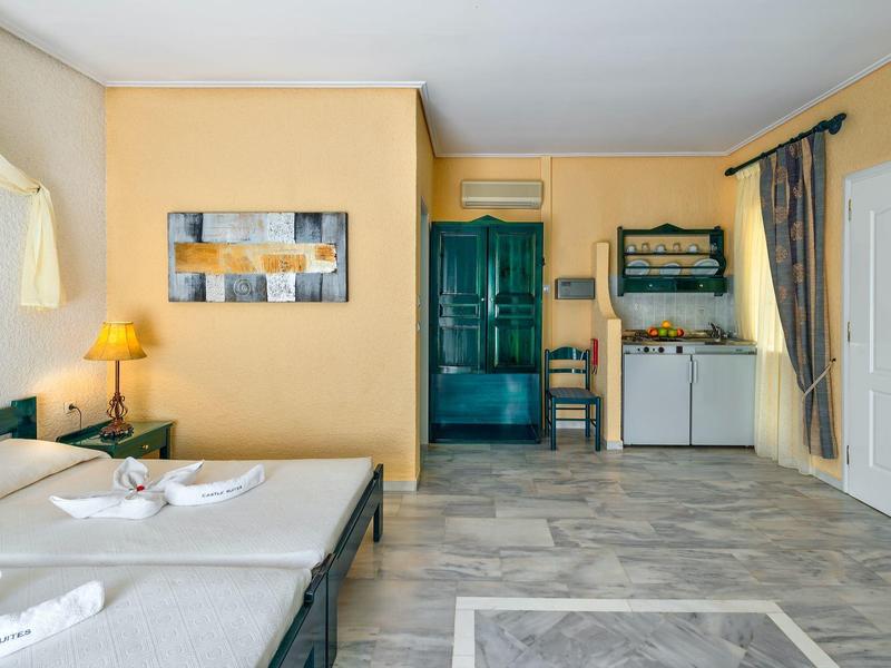 Licht ingerichte hotelkamer met twee eenpersoonsbedden, gele muren en grijze vloerbedekking.